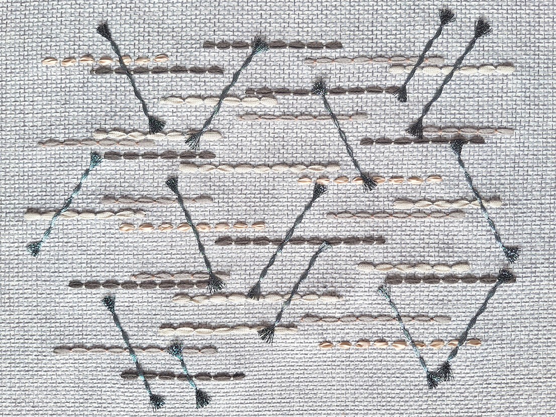 Close-up of geometric hand-stitched embroidery on beautifully textured fabric textile by P+L Studio, showcasing intricate French craftsmanship.